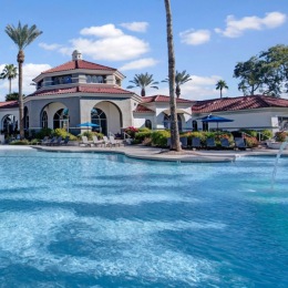 large pool with a building and palm trees in the background