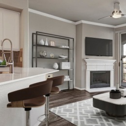 bar with barstools and living room in the background with a rug coffeetable and tv