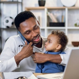 man holding a small child while talking on the phone